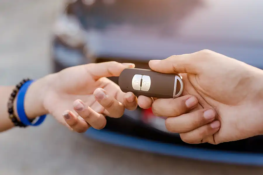 A person hands over a car key fob to another individual.