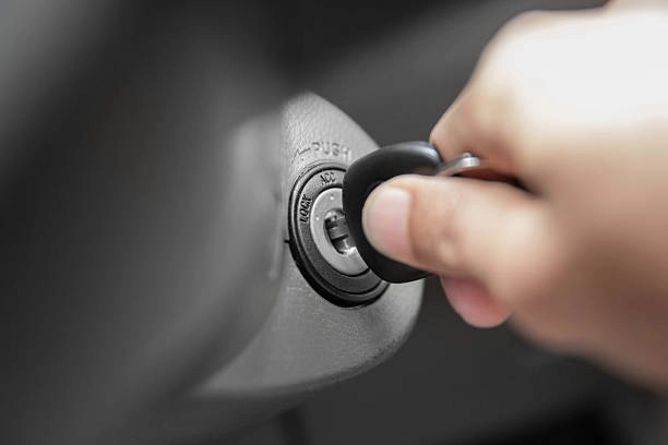 A hand inserting a key into the ignition of a vehicle.